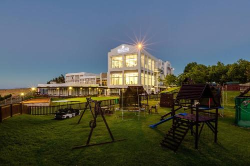 a large building with a playground in the grass at Protea Hotel by Marriott Stellenbosch & Conference Centre in Stellenbosch