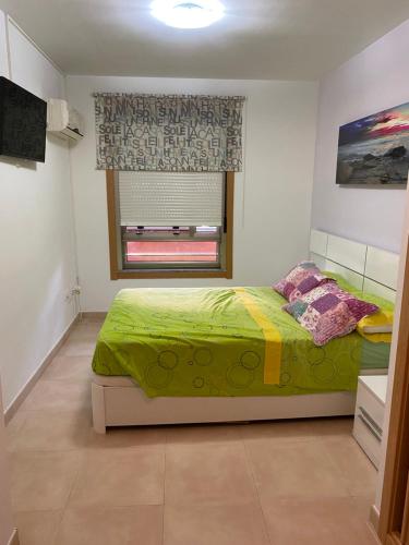 a bedroom with a green bed and a window at Algaida oropesa in Oropesa del Mar