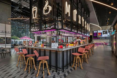 a bar with red stools in a restaurant at Moxy Bengaluru Airport Prestige Tech Cloud in Devanahalli-Bangalore