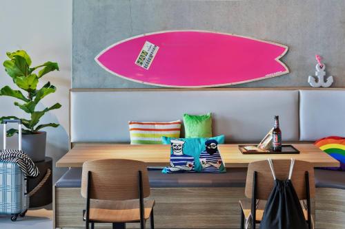 a dining room with a table and a pink surfboard at Moxy Hamburg City in Hamburg