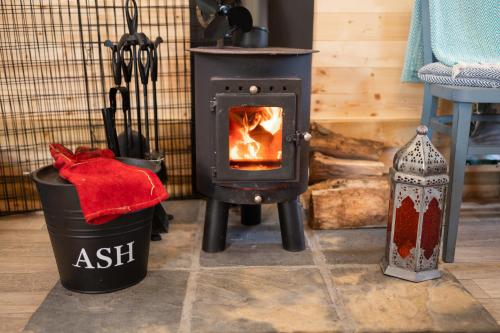 a wood stove in a room with a trash can at Hatters Meadows Glamping in Ely