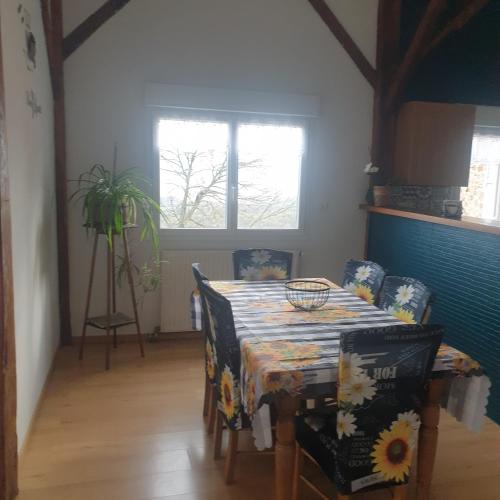 une salle à manger avec une table et des chaises et deux fenêtres dans l'établissement Appartement en campagne, à Taurignan-Castet