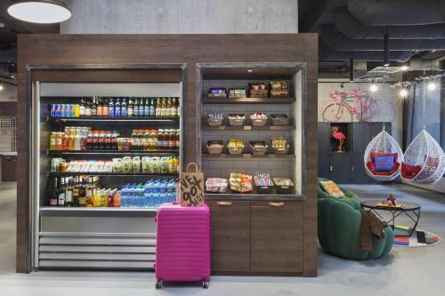 a soda shop with a pink suitcase in front of a refrigerator at Moxy Lausanne City in Lausanne