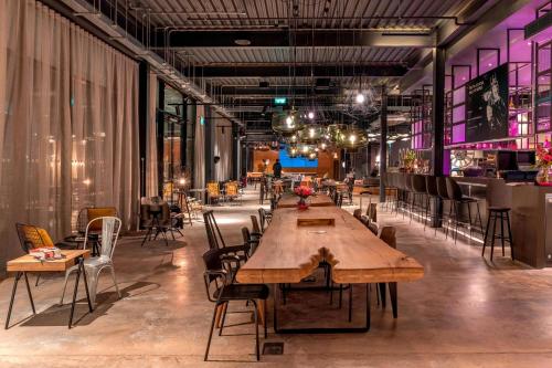 a large room with tables and chairs and a bar at Moxy London Heathrow Airport in Hounslow