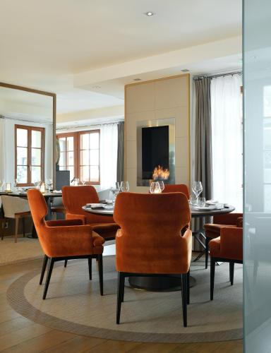 a dining room with orange chairs and a table at Le Strato in Courchevel