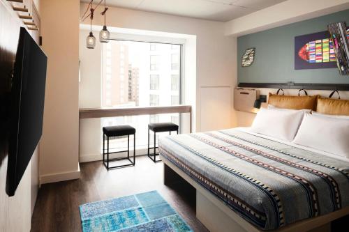 a bedroom with a bed and a window and a table at Moxy Halifax Downtown in Halifax