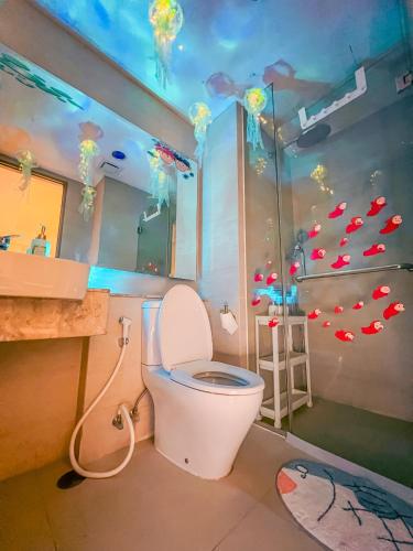 a bathroom with a toilet and a shower with fish on the wall at Gold Coast PIK Apartments by Host Jess in Jakarta