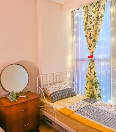 a bedroom with a bed and a mirror and a window at Gold Coast PIK Apartments by Host Jess in Jakarta