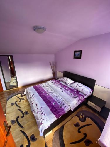 a bedroom with a bed with a purple comforter at Pensiunea Daiana in Albac