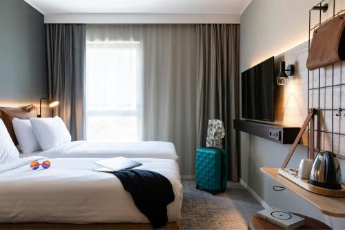 a hotel room with two beds and a television at Moxy Plymouth in Plymouth