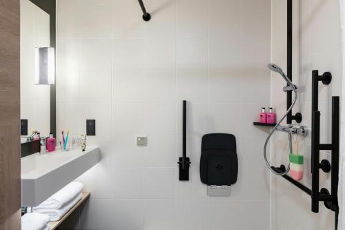 a white bathroom with a shower and a black chair at Moxy Plymouth in Plymouth