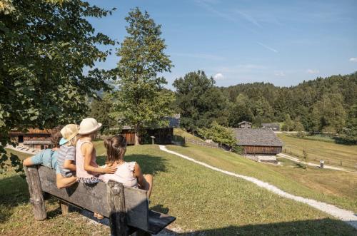 three people sitting on a bench looking at a farm at ROFANLODGE Gutschlhofer - House with Panoramic View in Tyrol, presented by AlpenLuxus in Mariatal