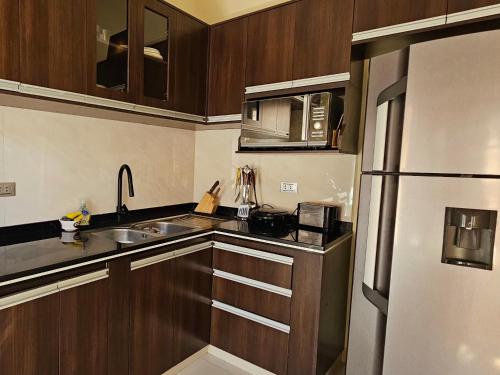 a kitchen with wooden cabinets and a stainless steel refrigerator at Casa Familiar "Chiqui" in Cochabamba