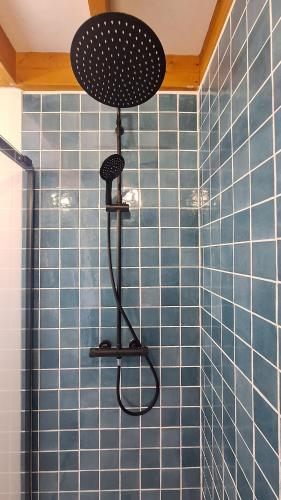 a shower with a shower head in a blue tiled bathroom at Jolie maison landaise proche de la plage in Messanges