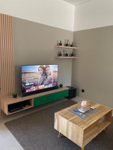 a living room with a flat screen tv and a coffee table at Ngumbara House in Tasikmalaya