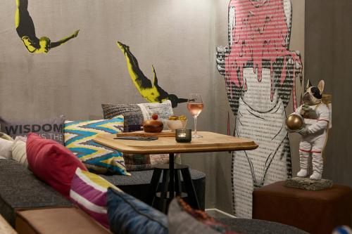 a living room with a table with a glass of wine at Moxy Patra Marina in Patra