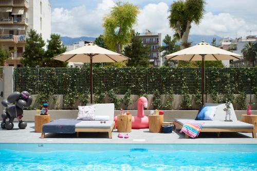 a pool with two lounge chairs and umbrellas next to a pool at Moxy Patra Marina in Patra