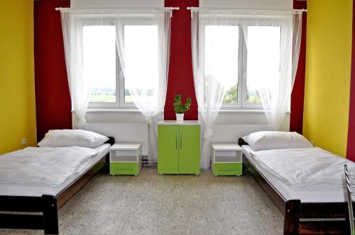 two beds in a room with two windows at Penzion První Liga in Hradec Králové