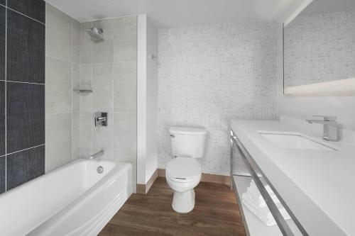 a bathroom with a toilet and a tub and a sink at Orlando Marriott Lake Mary in Lake Mary