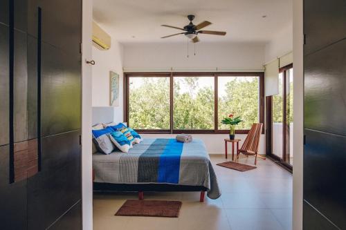 a bedroom with a bed and a large window at Serene Jungle Villa -Steps from the Ocean in Akumal