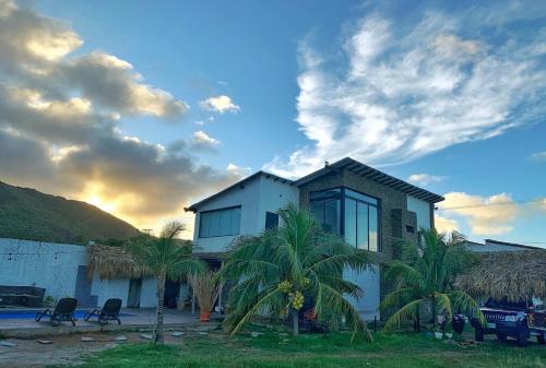 a house with palm trees in front of a building at Casa a pasos del mar de Playa el Agua in La Loma
