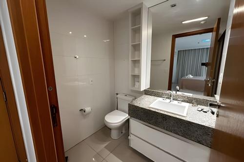 a bathroom with a toilet and a sink and a mirror at Brisas do Lago - Apartamento 6 in Brasilia