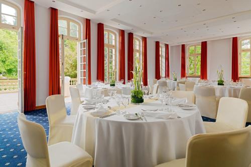 a room with white tables and white chairs and windows at Sheraton Offenbach Hotel in Offenbach