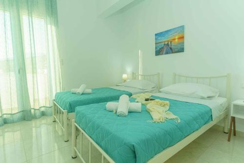 two beds in a room with blue sheets at Cocoscape Seaside Suite, With Sea View in Kalamaki Heraklion