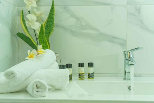 a bathroom sink with towels and a vase of flowers at Cocoscape Seaside Suite, With Sea View in Kalamaki Heraklion