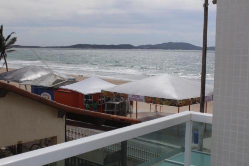 a boat on the beach with umbrellas on a balcony at Paradiso Peró Praia Hotel in Cabo Frio