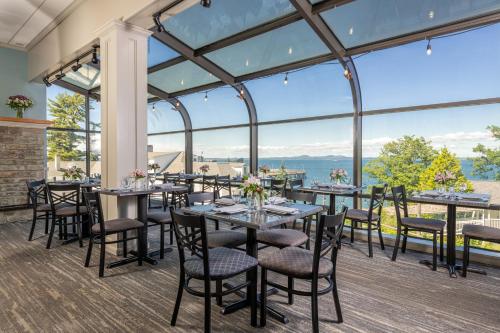 a dining room with tables and chairs and large windows at Atlantic Oceanside Hotel & Conference Center in Bar Harbor
