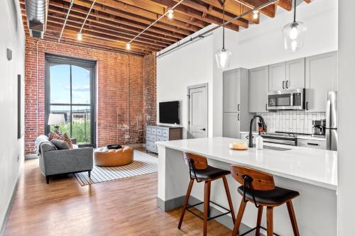 an open kitchen and living room with a brick wall at Brick & Bed Riverfront Lofts, G 209 in Saint Louis