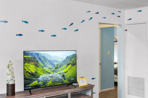a living room with a tv and a wall with birds decals at Vintage Vibes - Grill, Chill & Beach Thrills in Sarasota