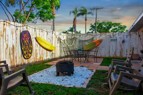 a backyard with a fire pit and surfboards on a fence at Vintage Vibes - Grill, Chill & Beach Thrills in Sarasota
