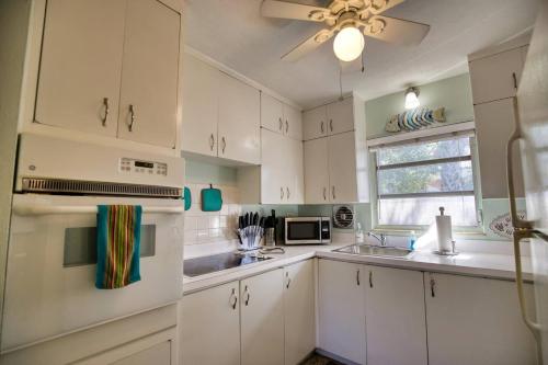 a kitchen with white cabinets and a sink and a window at Vintage Vibes - Grill, Chill & Beach Thrills in Sarasota