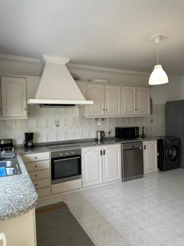 a kitchen with white cabinets and a stove top oven at Extraordinary Holiday House at Fernão Ferro! in Fernao Ferro
