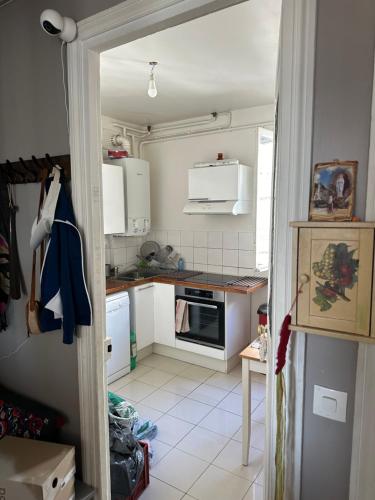 Il comprend une cuisine avec des placards blancs et du carrelage blanc. dans l'établissement Chambre touristique, à Paris