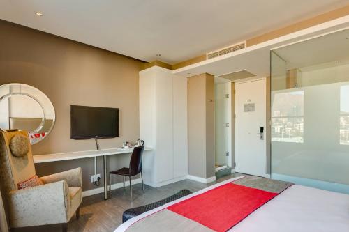 a bedroom with a bed and a television and a chair at Protea Hotel by Marriott Cape Town Waterfront Breakwater Lodge in Cape Town
