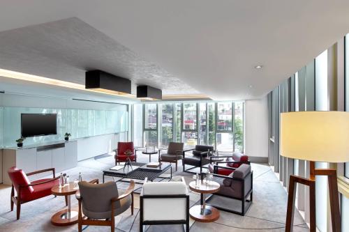 a living room with chairs and tables and a tv at Le Meridien Istanbul Etiler in Istanbul