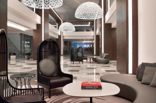 a lobby with chairs and tables and chandeliers at Le Meridien Istanbul Etiler in Istanbul
