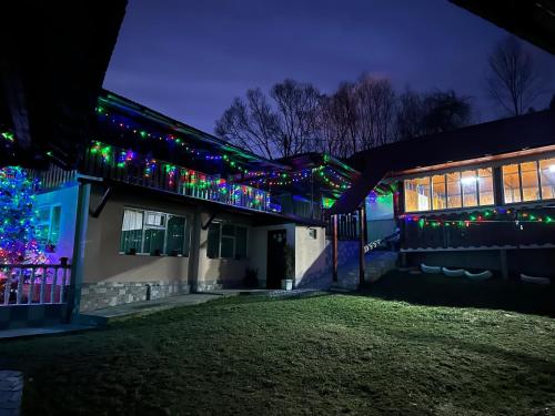 a house with christmas lights on the side of it at Pensiunea Daiana in Albac