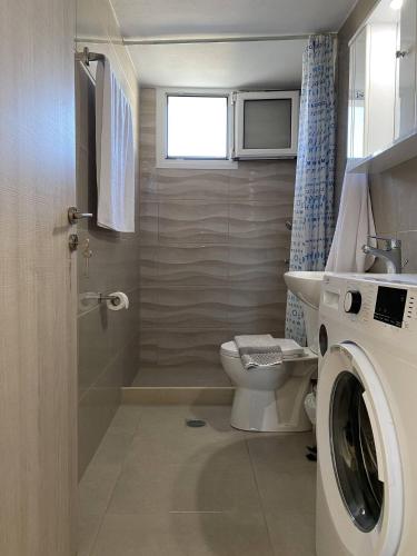 a bathroom with a toilet and a washing machine at Orphanos Apartment in Kamilari