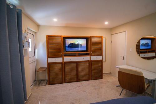 a living room with a flat screen tv and a desk at Inti Relax Garden Suite in Oranjestad