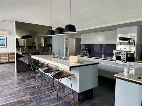 a kitchen with a large island with bar stools at Iconic & Curvaceous Beach House in Waikanae