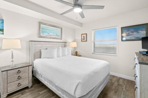 a white bedroom with a bed and a television at Pelican Isle 313 in Fort Walton Beach
