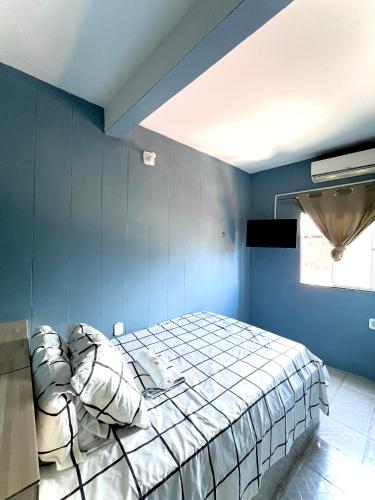 a bedroom with blue walls and a bed with pillows at Pousada Realce - Próximo ao Ferry Boat in Itaparica Town