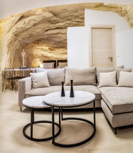 a living room with a couch and two tables at Theasis Luxury Cave House, With Sea & Cave View in Matala