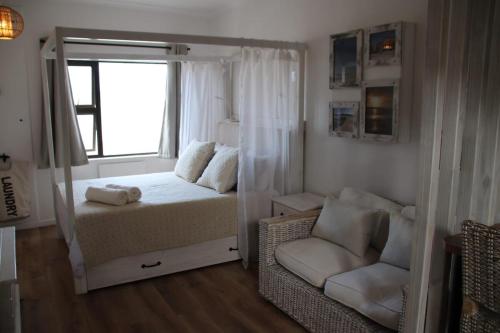 a bedroom with a bed and a window and a chair at Cozy Lounge - Visit Langebaan in Langebaan