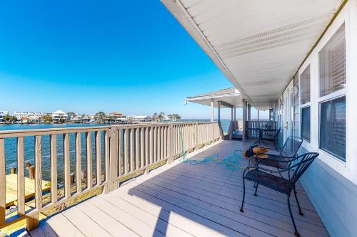 a porch with two chairs and a view of the water at Bay Dream Believer in Dauphin Island