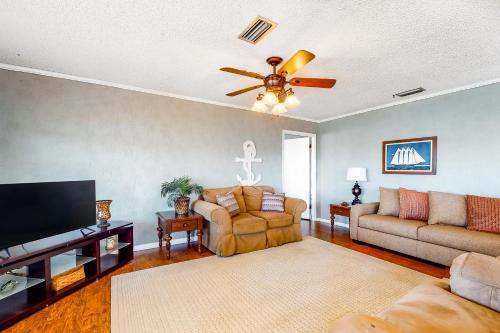 a living room with a couch and a ceiling fan at Bay Dream Believer in Dauphin Island